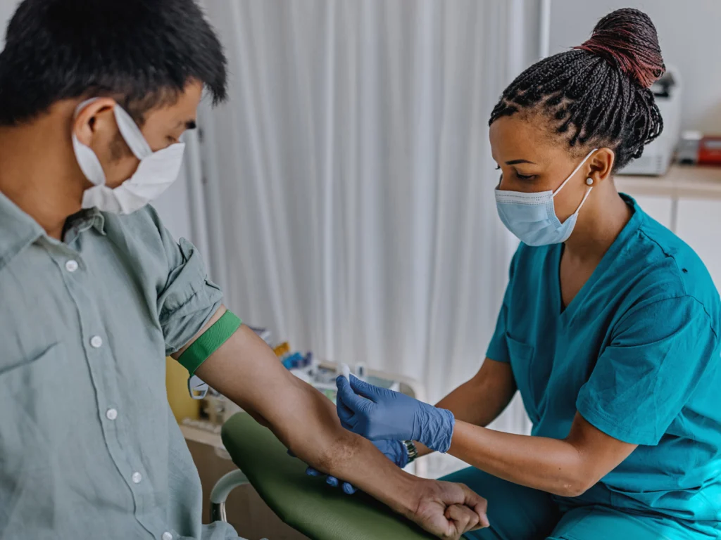 Nurse drawing blood from masked patient