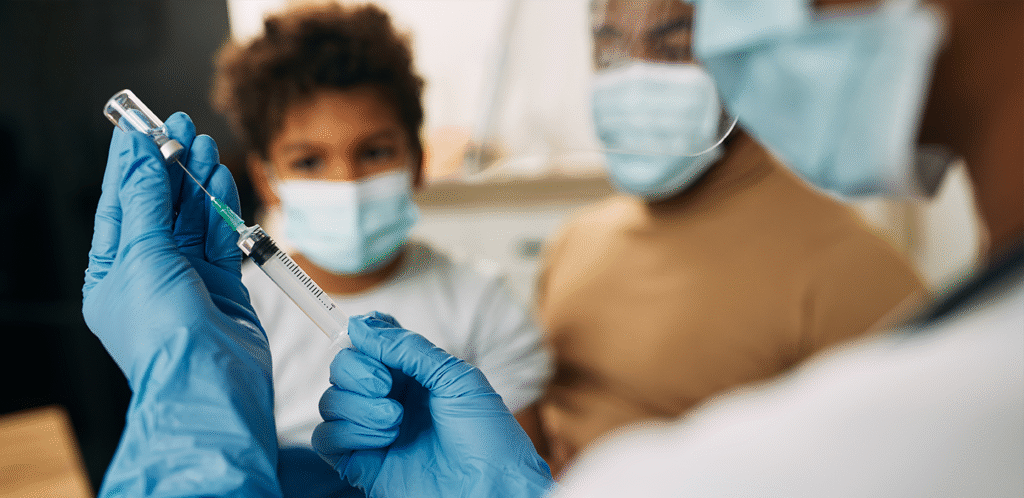 Healthcare worker preparing vaccine while masked children watch