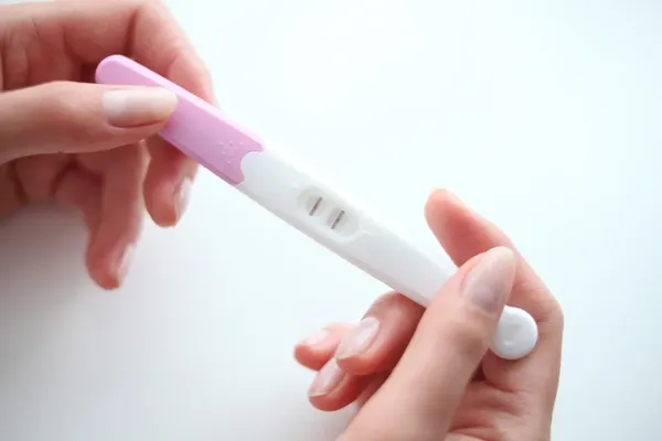 Hands holding positive pregnancy test